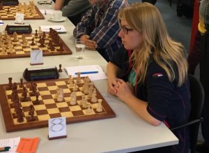 Schaakster Leonore Braggaar achter een schaakbord tegen de Westlandse Schaak Combinatie